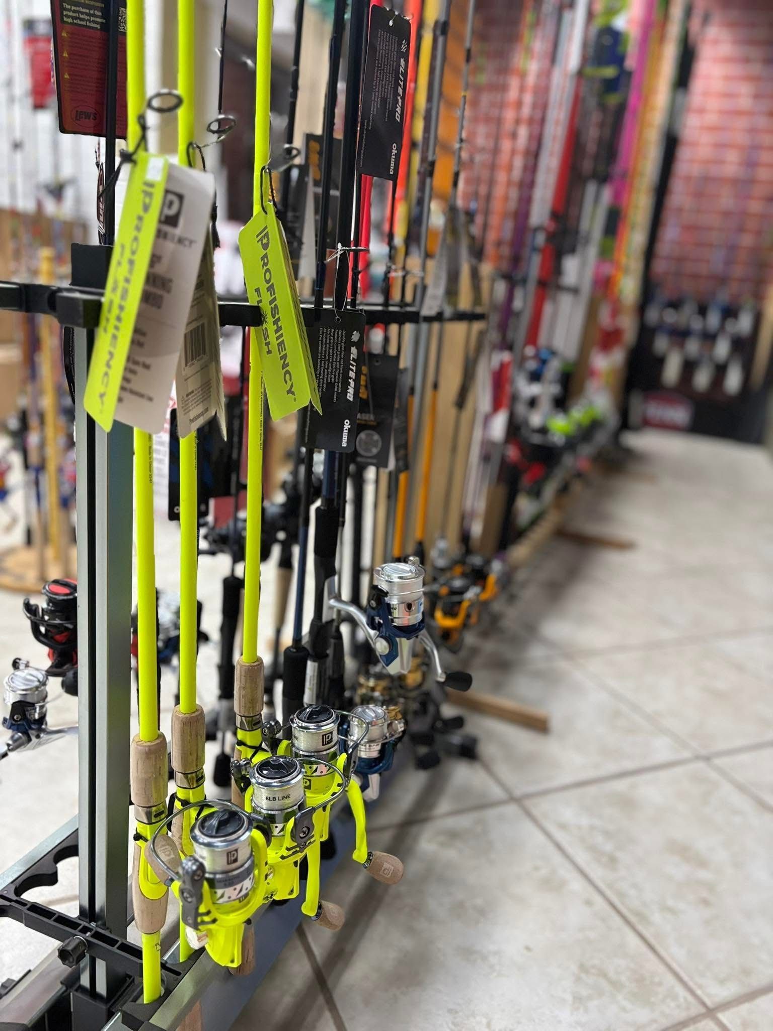 A row of fishing rods are lined up on display in a store.