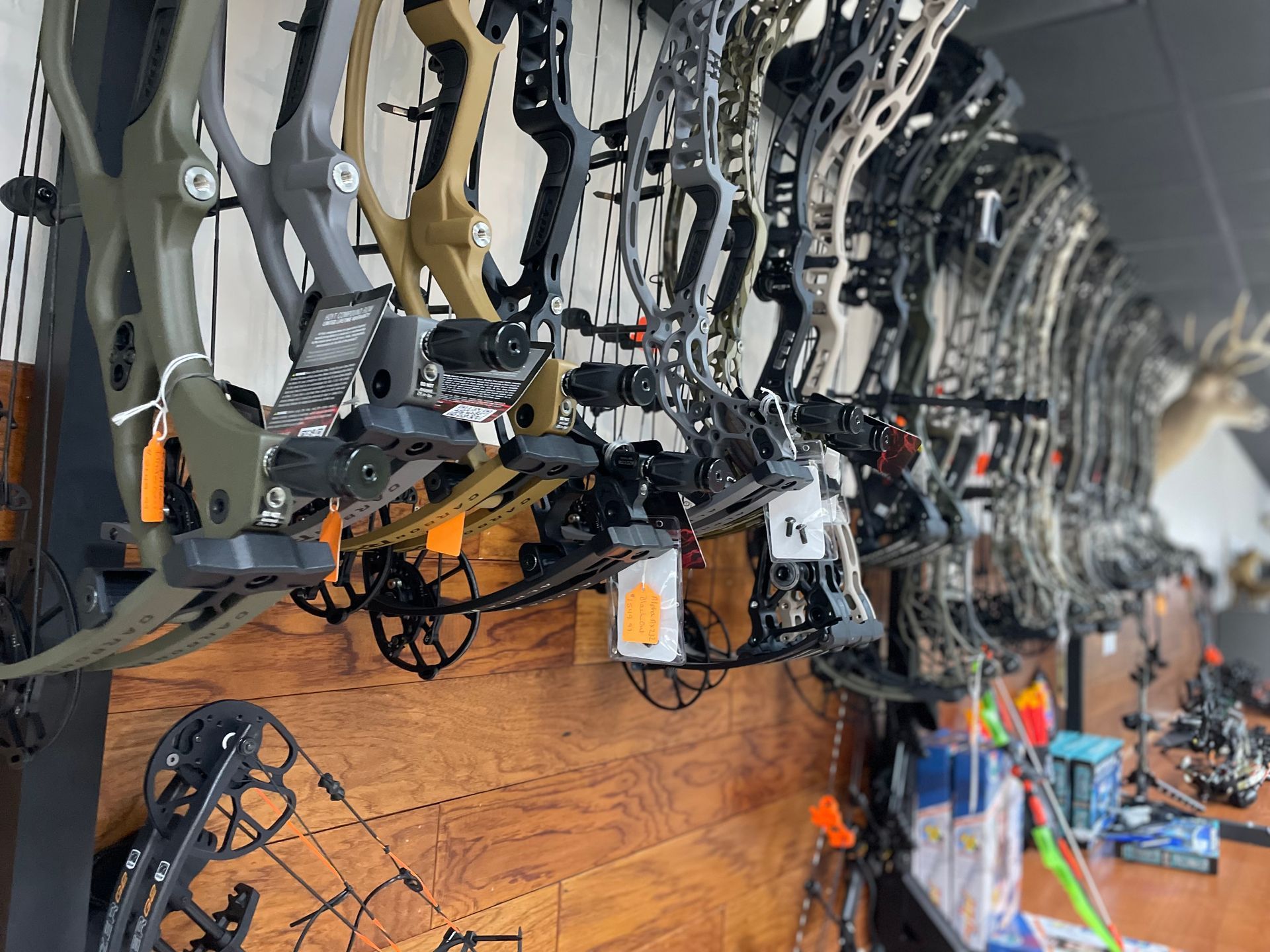A row of bows and arrows hanging on a wall in a store.