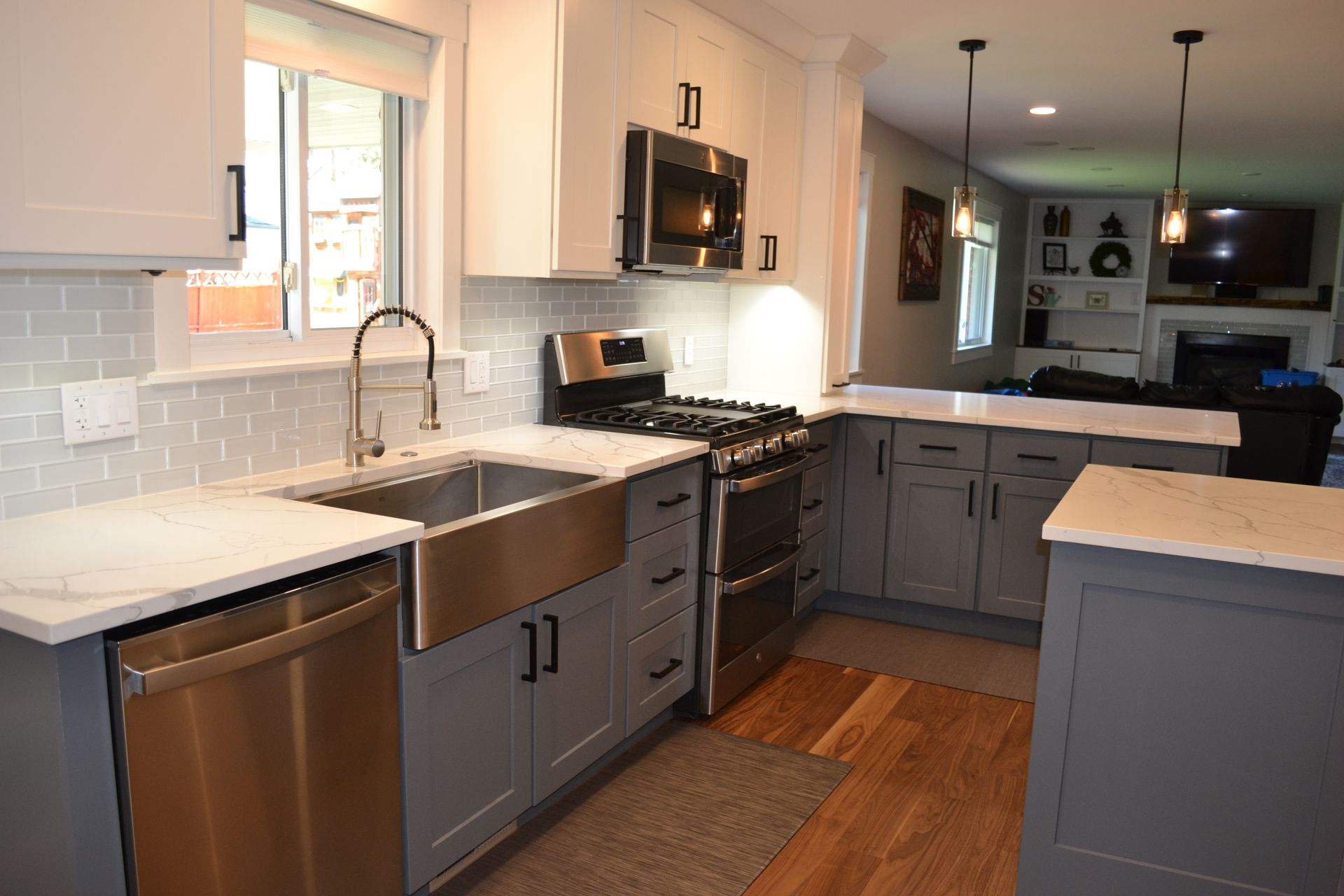Modern kitchen with stainless steel appliances, gray and white cabinets, and a farmhouse sink.