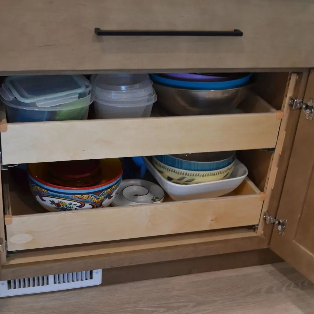 Kitchen cabinet with pull-out drawers filled with bowls and containers.