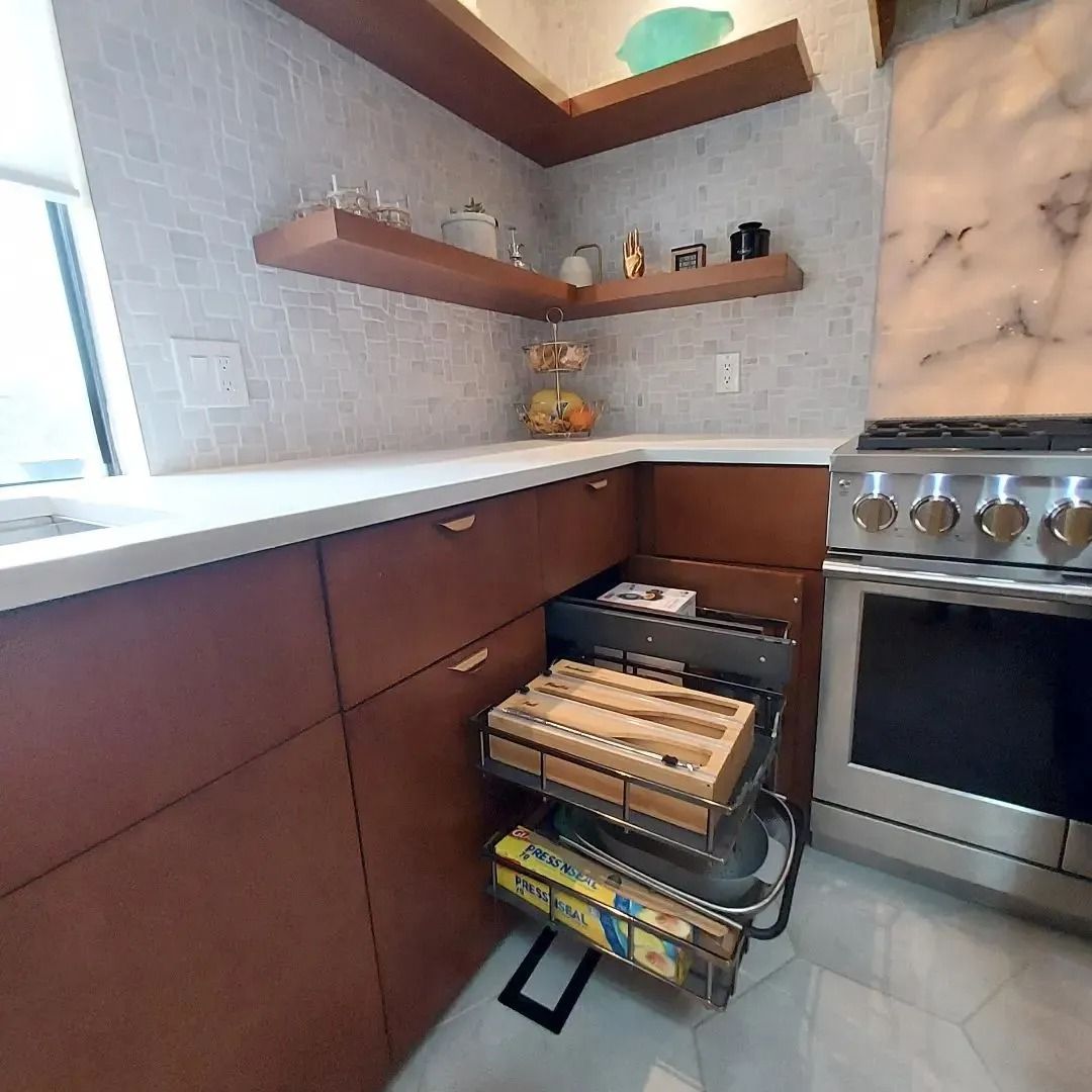 Kitchen with brown cabinets, white countertops, and stainless steel oven. Floating shelves with decor.