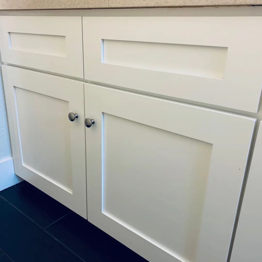 White cabinet doors with silver knobs and dark floor.