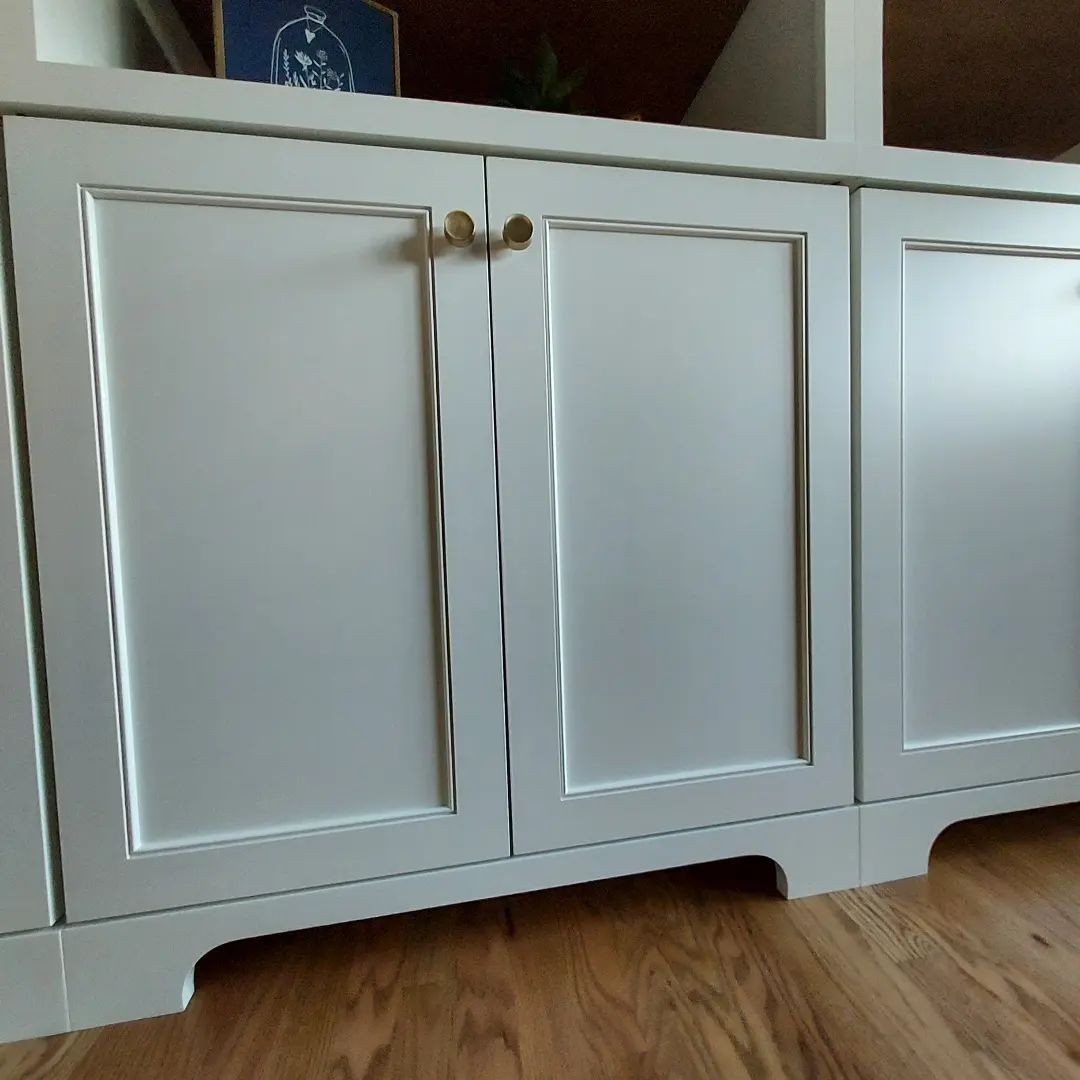 White cabinet doors with gold hardware on a wooden floor.
