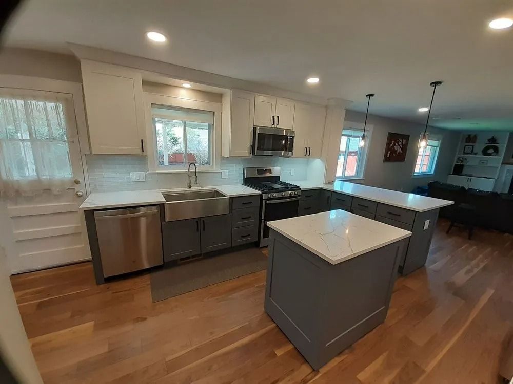Modern kitchen with gray and white cabinets, stainless steel appliances, and two islands.