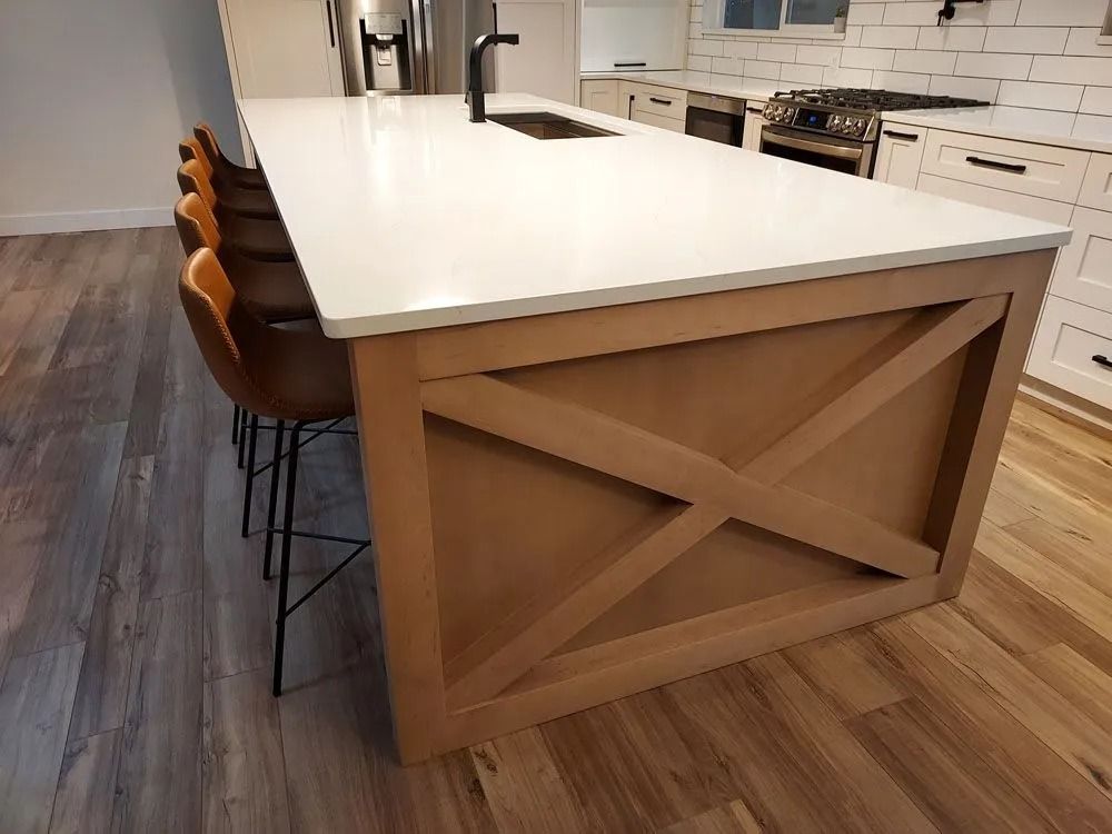 Kitchen island with white countertop, wooden X design, and brown bar stools.