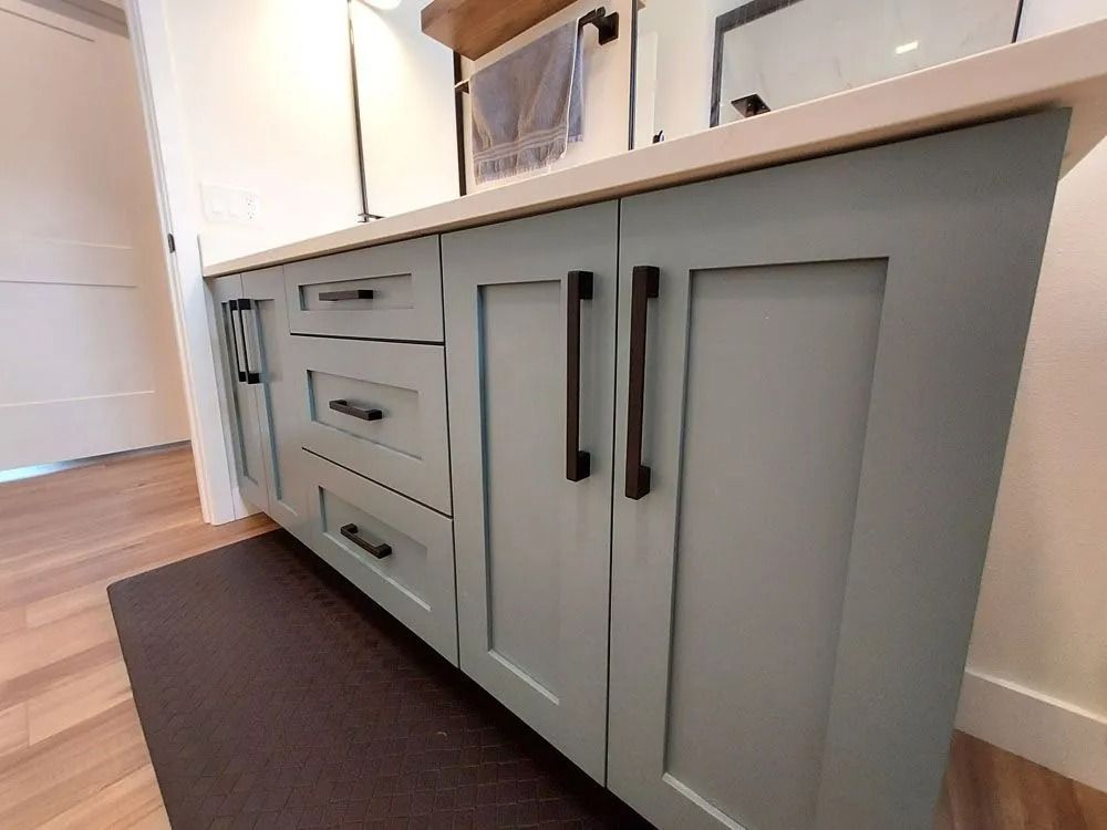 Light blue bathroom vanity with black hardware and drawers.