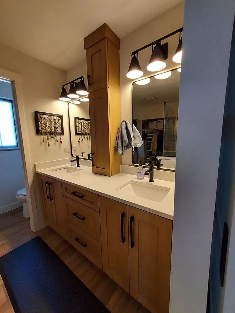 Bathroom with wooden vanity, black fixtures, and mirrors.