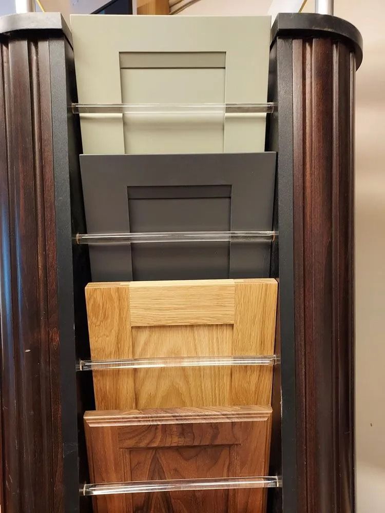 Cabinet door samples displayed in a vertical rack, showing different colors and wood grains.