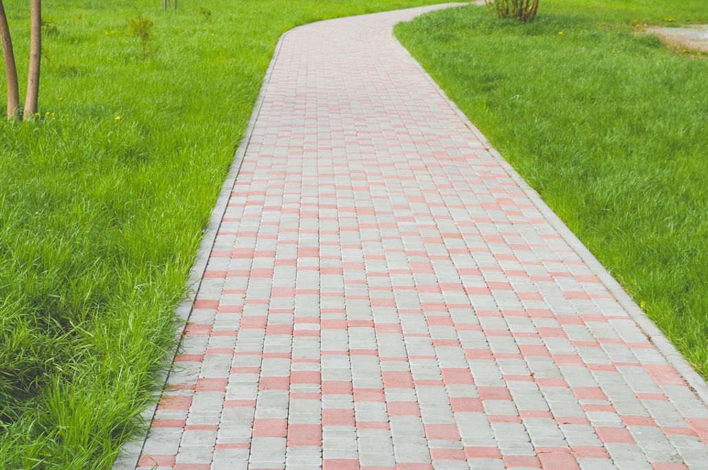 Brick walkway through a green lawn in a park-like setting