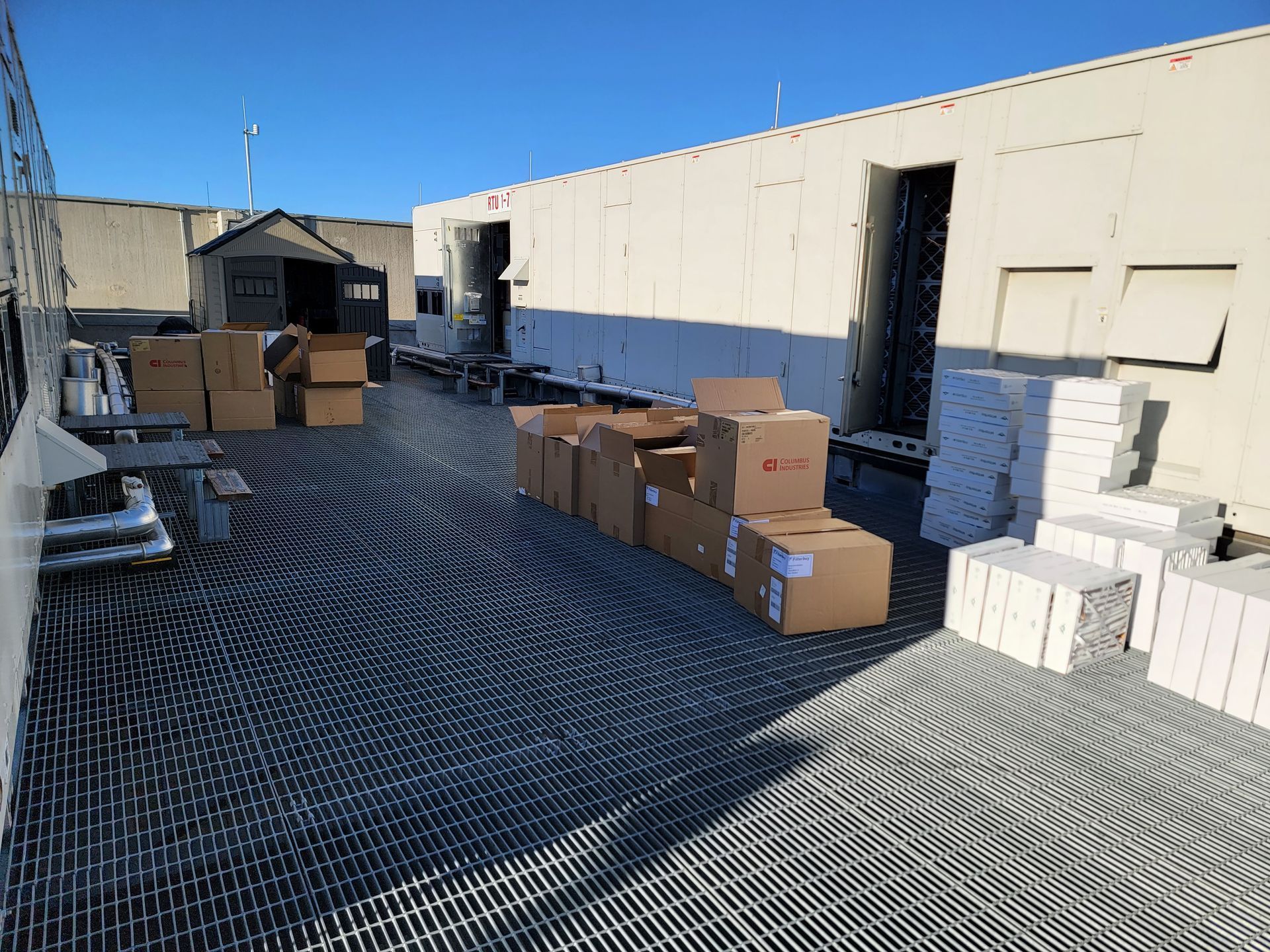 White air conditioner mounted on a wall above white window blinds in a room.