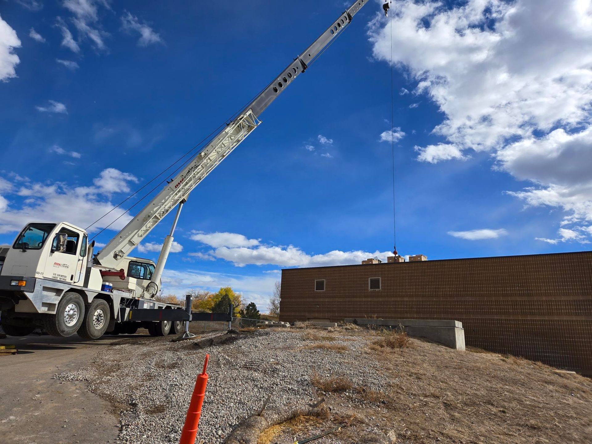 Two people loading boxes onto a roof with a building and shed. White and brown boxes are stacked near them on a metal grid.