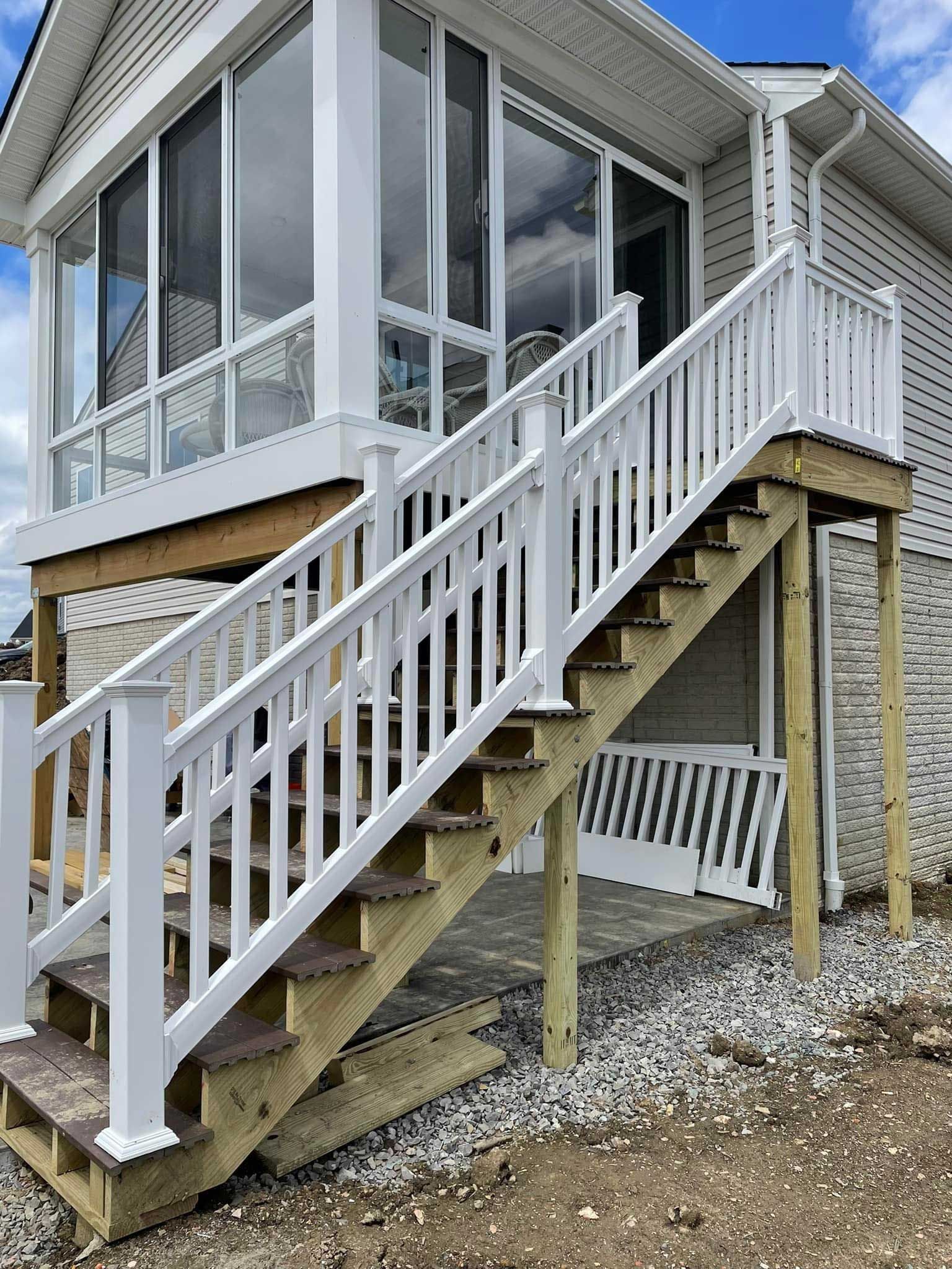 White stair railing leading to screened porch entrance on a brick house.