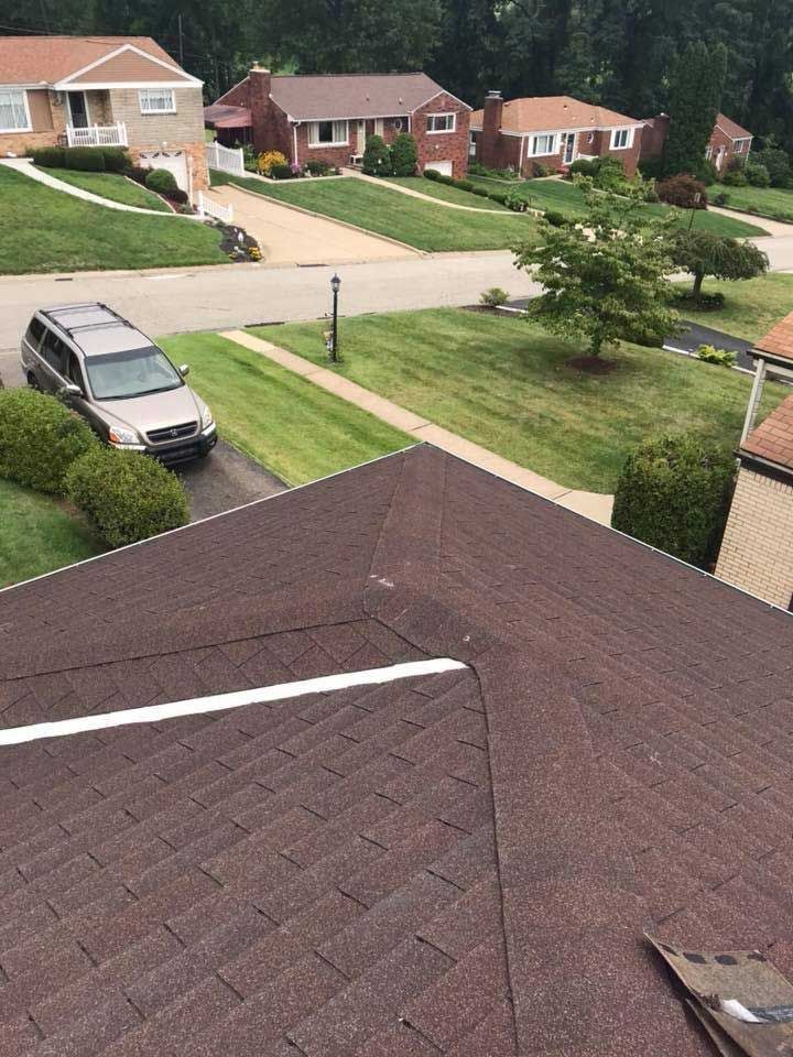 Brown shingled roof with a view of a suburban neighborhood.