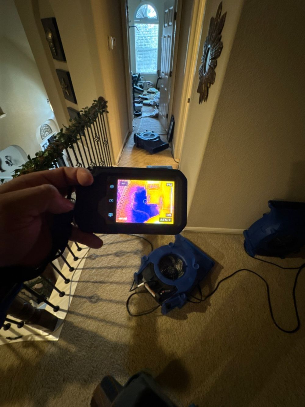A person is holding a thermal camera in a hallway.