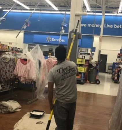 Person mopping a Walmart aisle near clothing racks and a blue service sign.