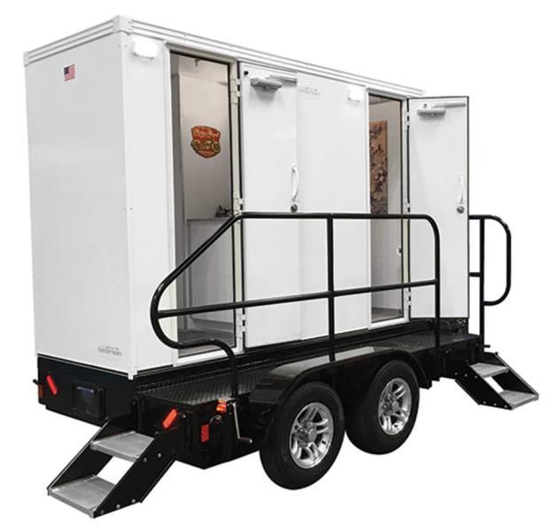 A white restroom trailer with a black railing and stairs