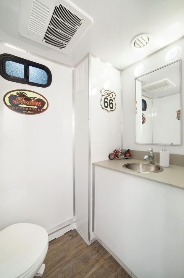 A portable bathroom with a toilet, sink and mirror