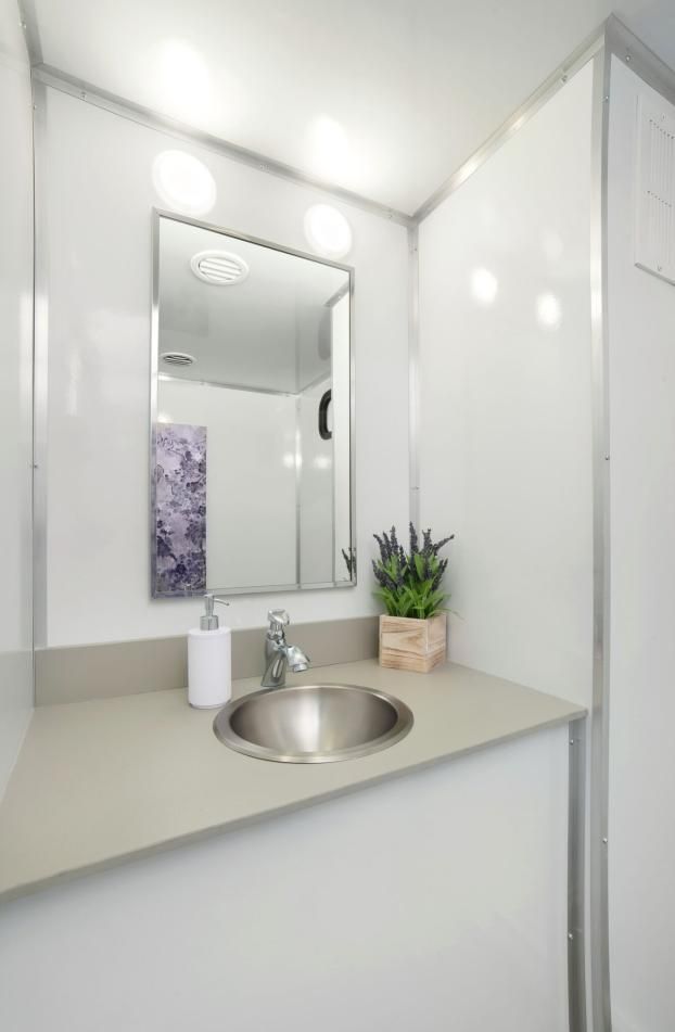 A portable bathroom with a sink, mirror and plant