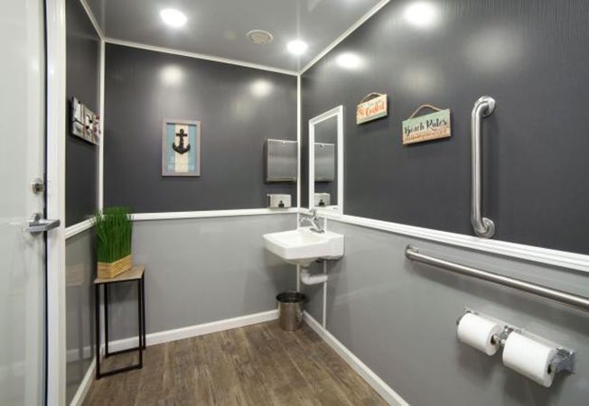 A portable bathroom with a sink, mirror, and toilet paper