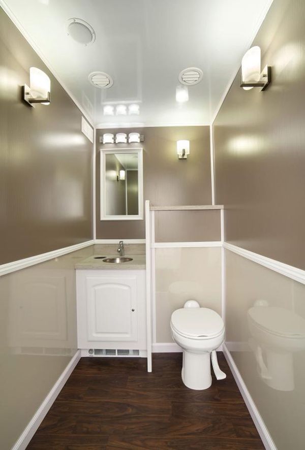 A portable bathroom with a toilet, sink and mirror