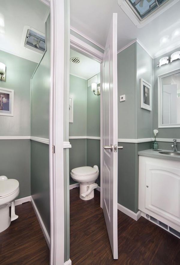 A portable bathroom with a toilet, sink and mirror