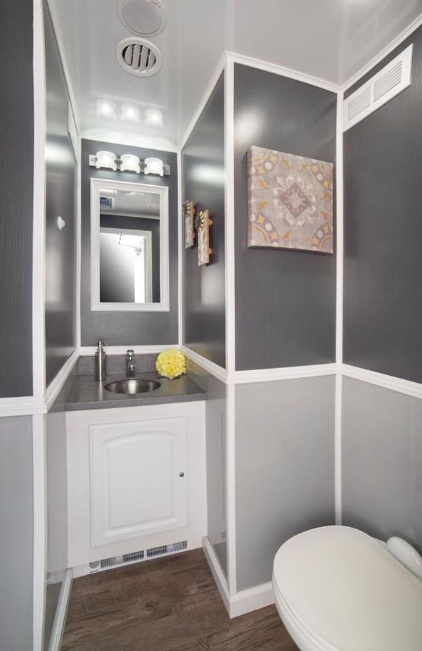 A portable bathroom with a sink, toilet and mirror