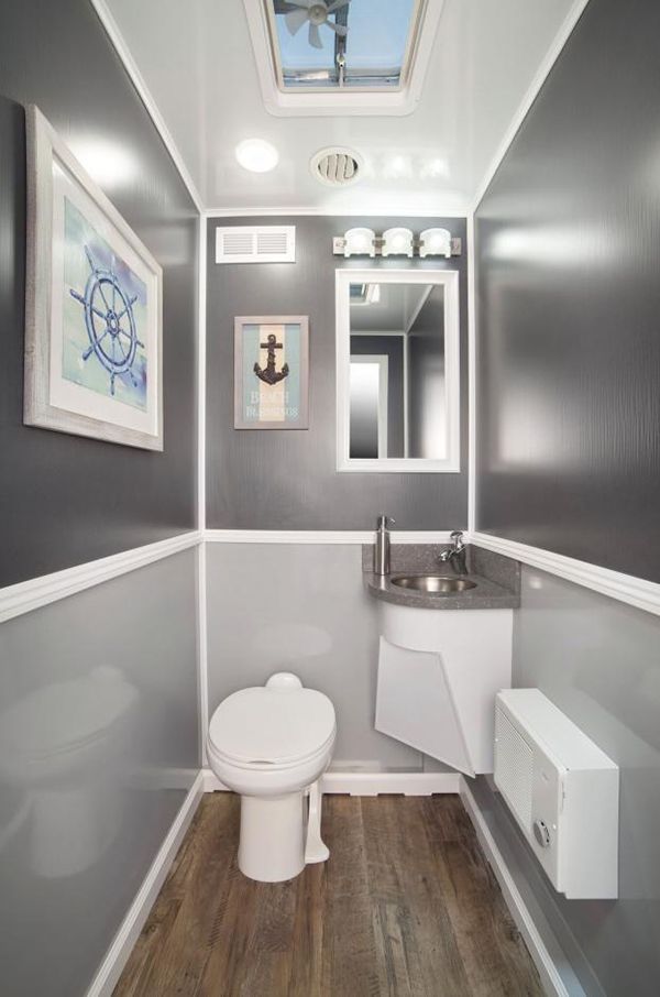 A portable bathroom with a toilet, sink, mirror and skylight