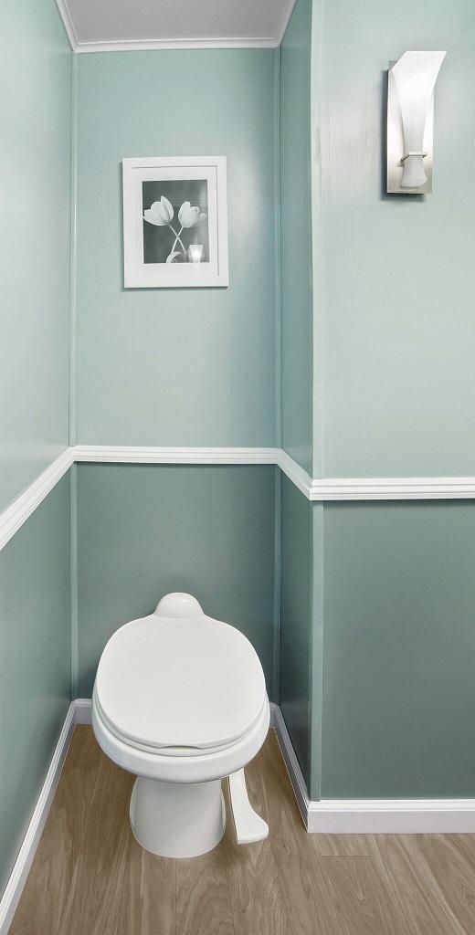 A small portable bathroom with a toilet and a picture on the wall