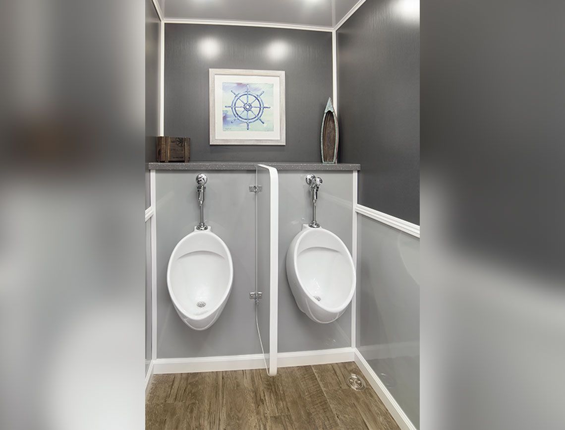 a bathroom with two urinals and a picture on the wall .