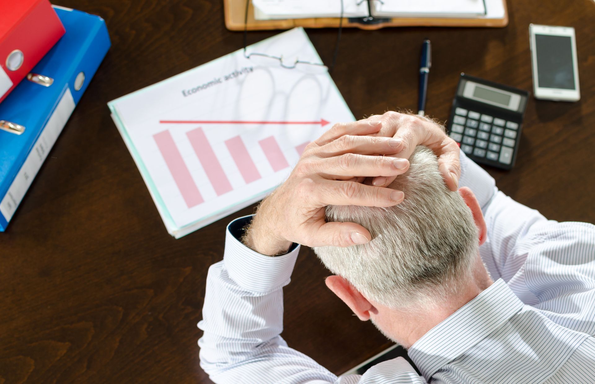 Person with head in hands, looking at a downward trending graph labeled