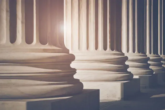 Row of classical columns with ornate capitals, bathed in sunlight.