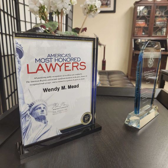 Two awards on a dark desk. One framed, 