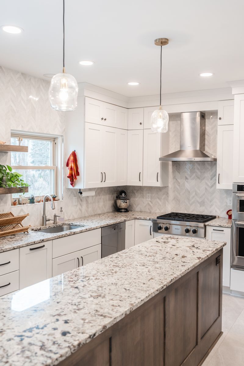 A kitchen with granite counter tops , white cabinets , stainless steel appliances and a large island.