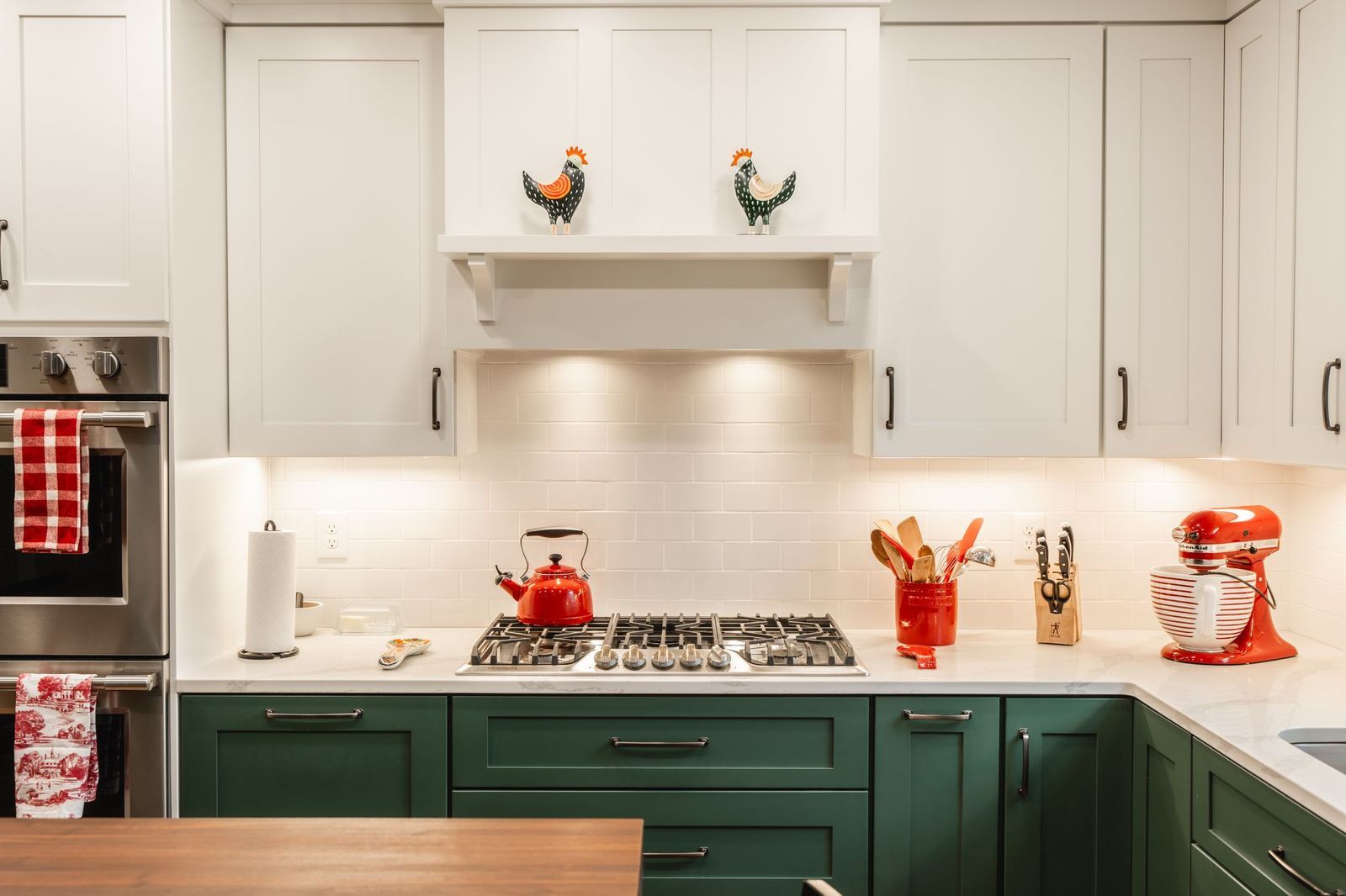 A kitchen with green cabinets and white cabinets and a stove top oven.