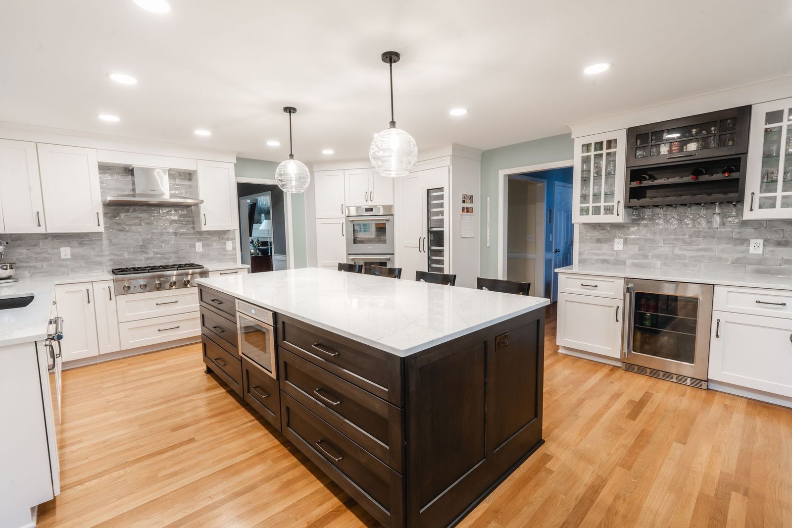 A kitchen with white cabinets and stainless steel appliances and a large island in the middle.
