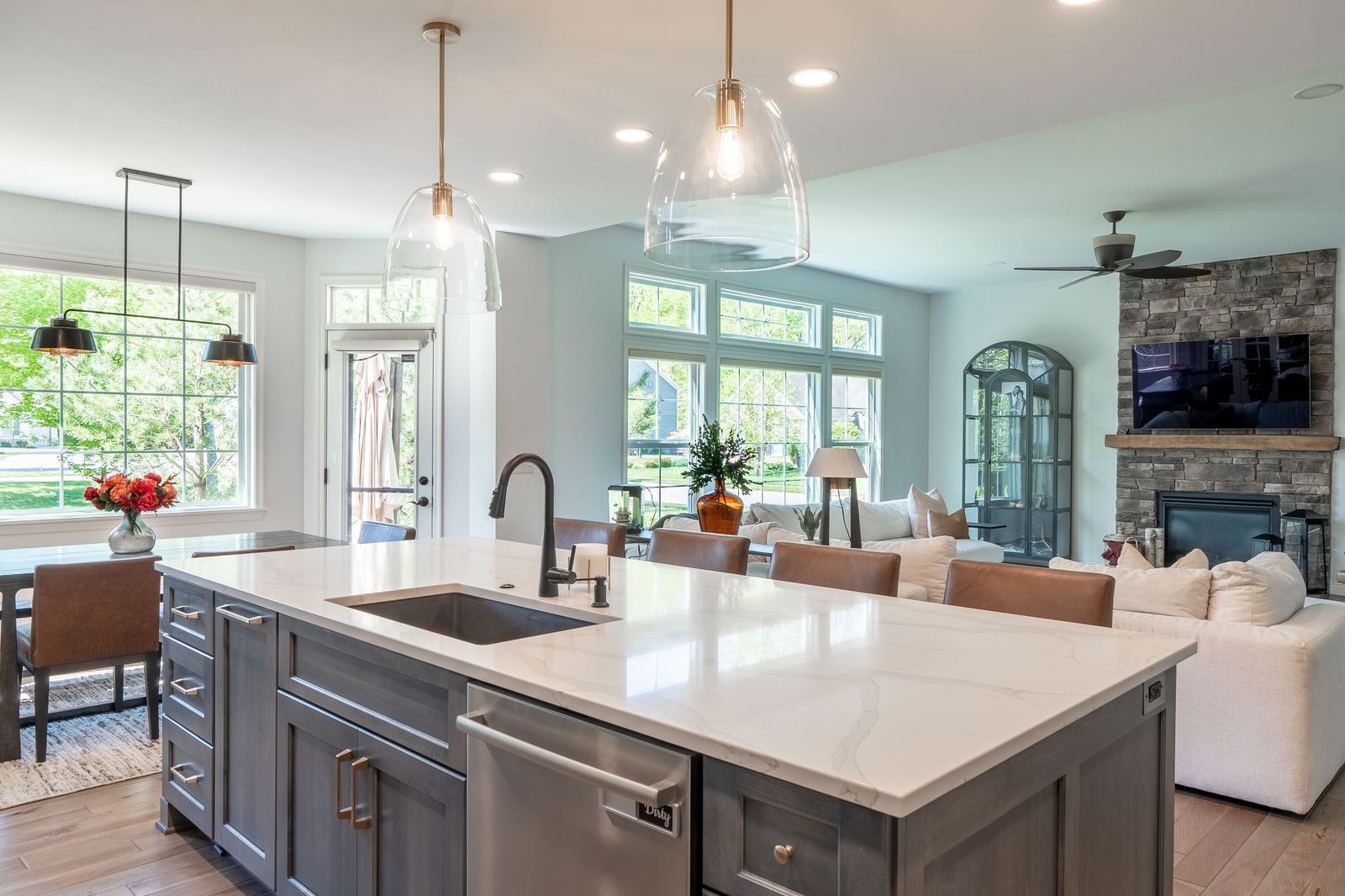 A kitchen with a large island , sink , dishwasher and stainless steel appliances.