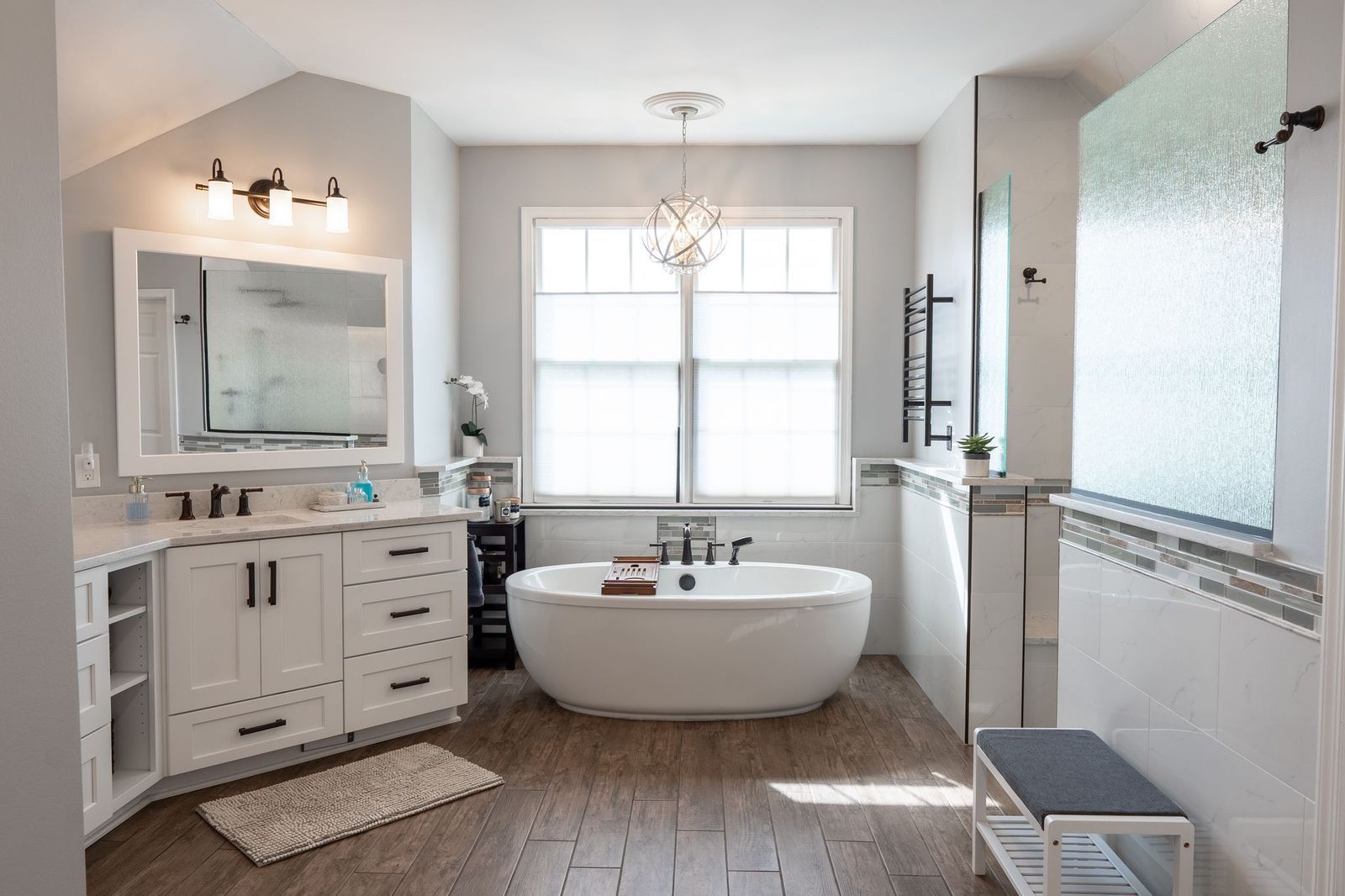 A bathroom with a tub , sink , mirror and window.