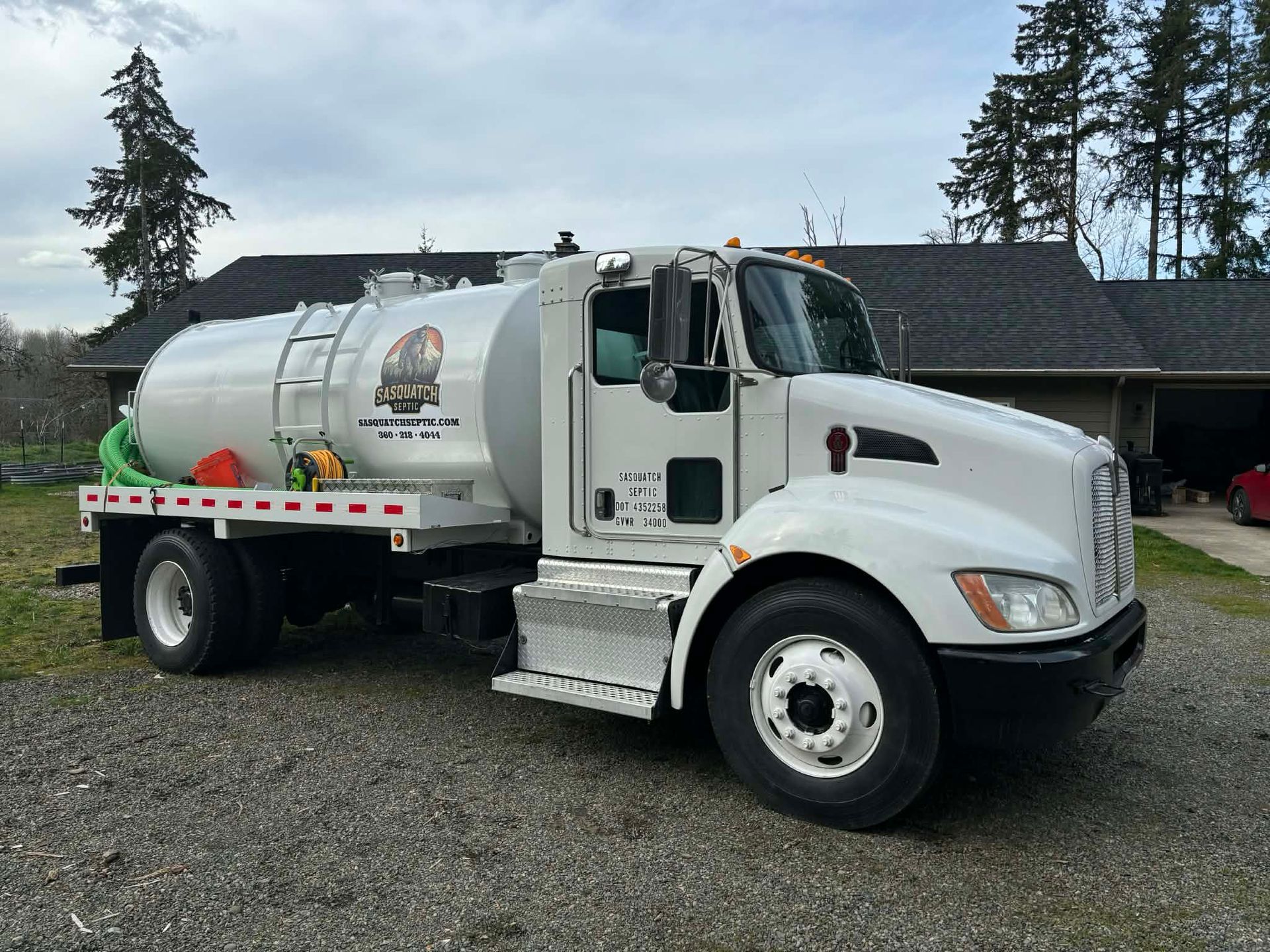 White septic tank truck parked on gravel driveway.