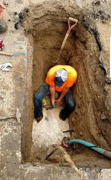 A man is digging a hole in the ground with a shovel.