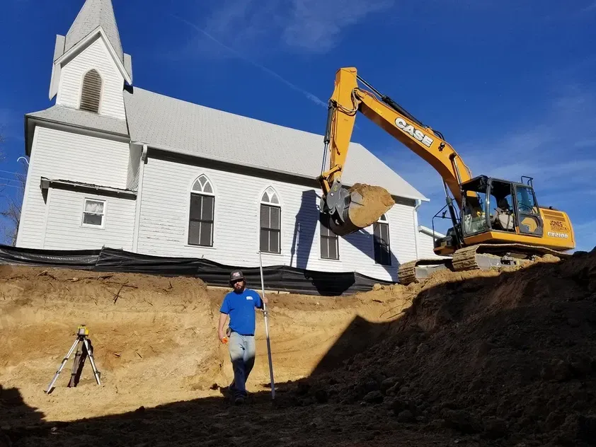 A man stands in front of a large excavator that says case