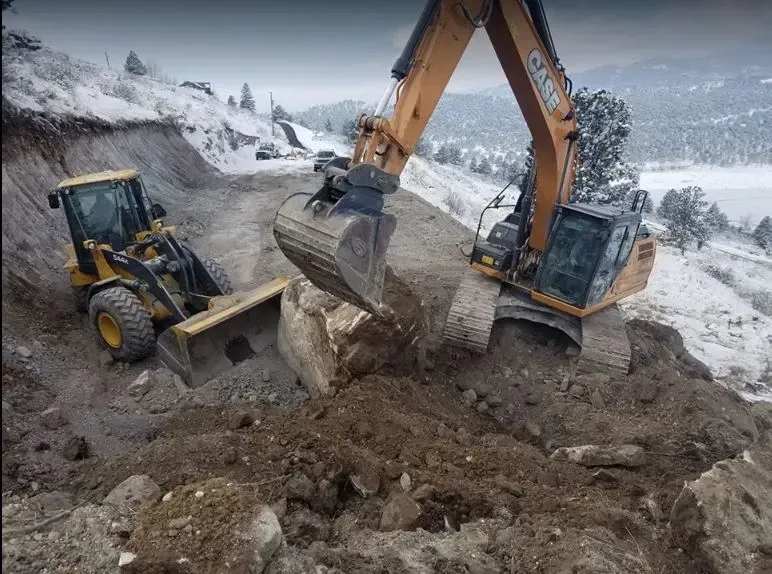 A couple of excavators are digging a hole in the ground.