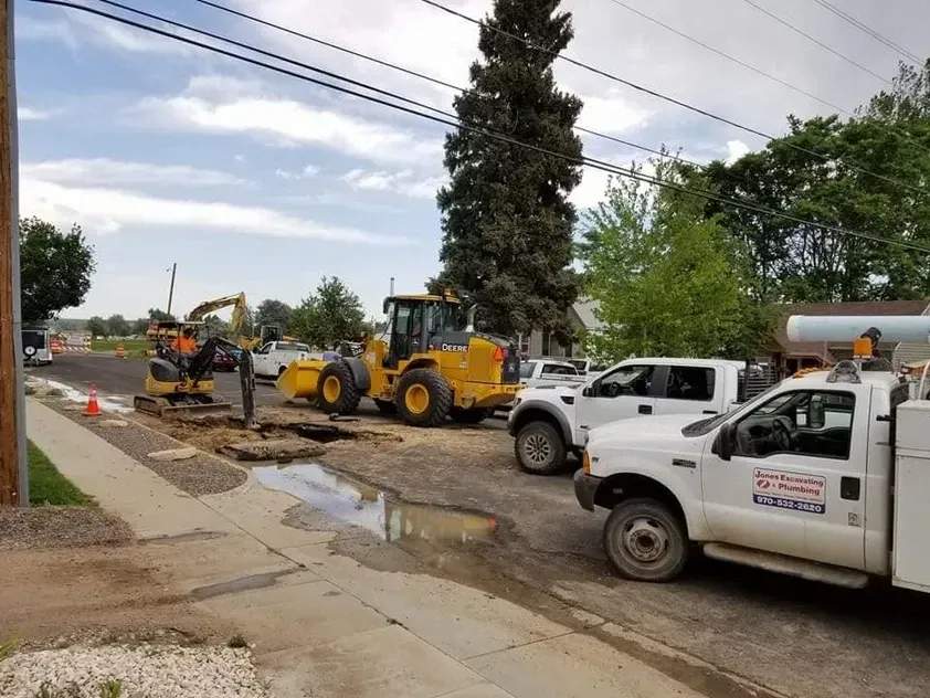 A white truck is parked on the side of the road next to a yellow tractor.