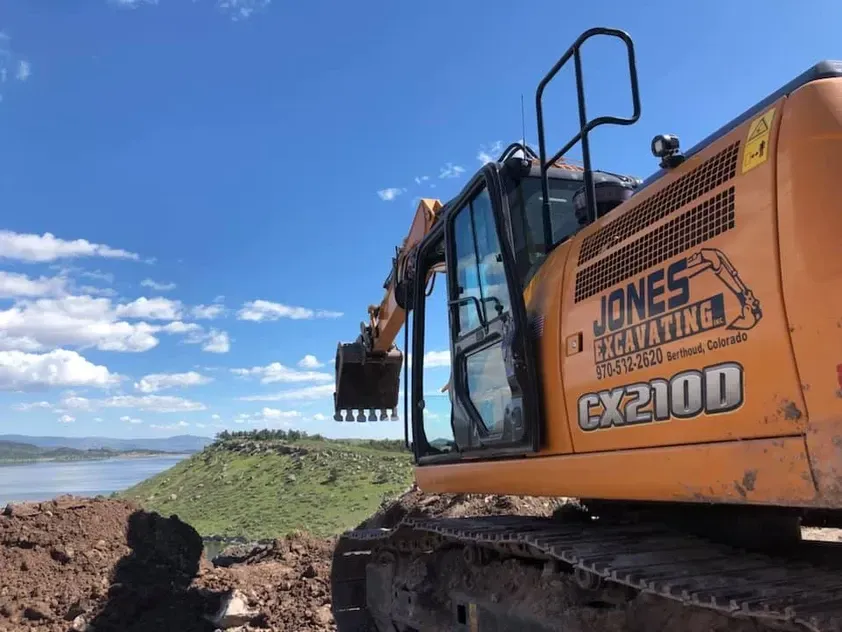 A large excavator is sitting on top of a dirt hill.