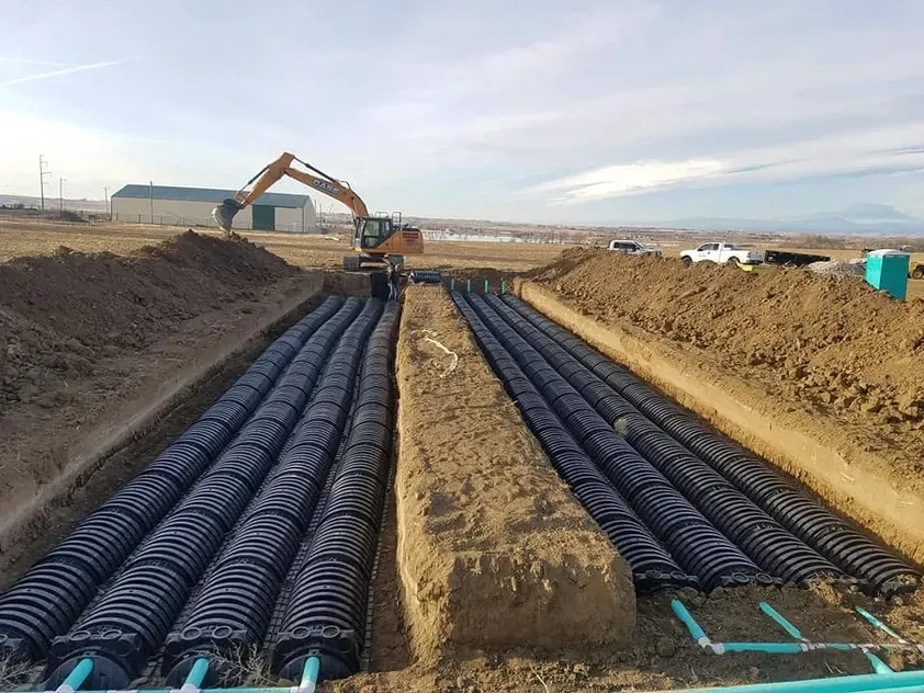 A construction site with a lot of pipes in the dirt.