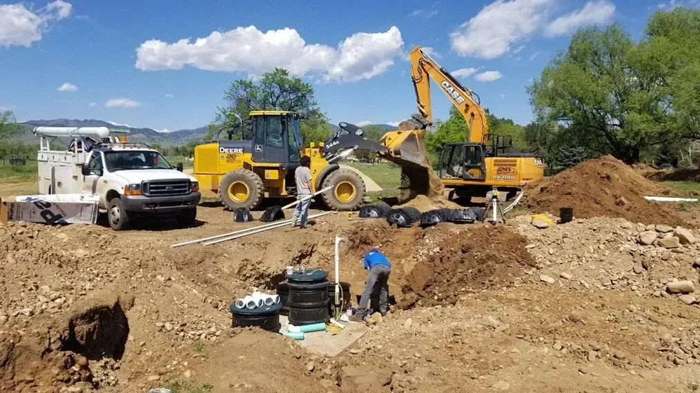 A group of construction vehicles are working on a dirt field.