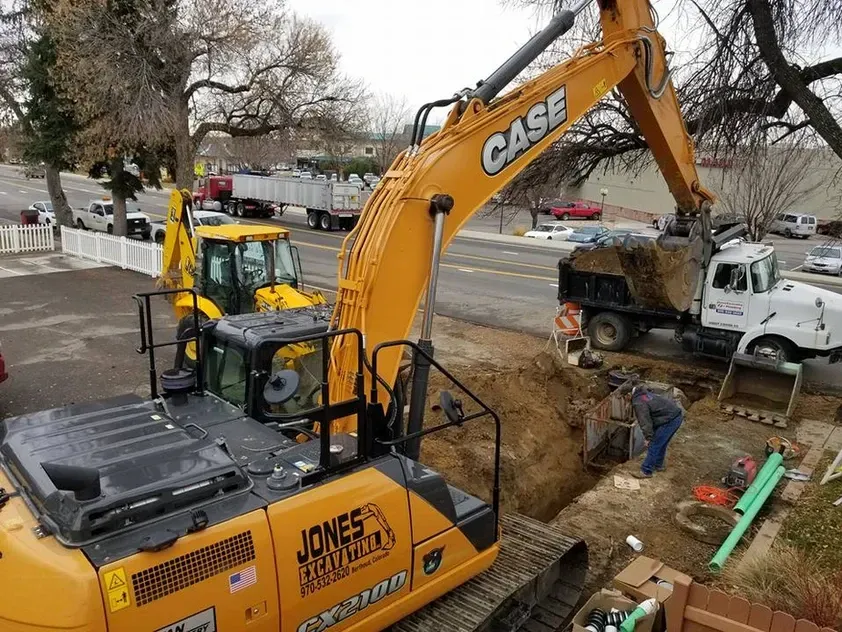 A yellow case excavator is digging a hole in the ground.