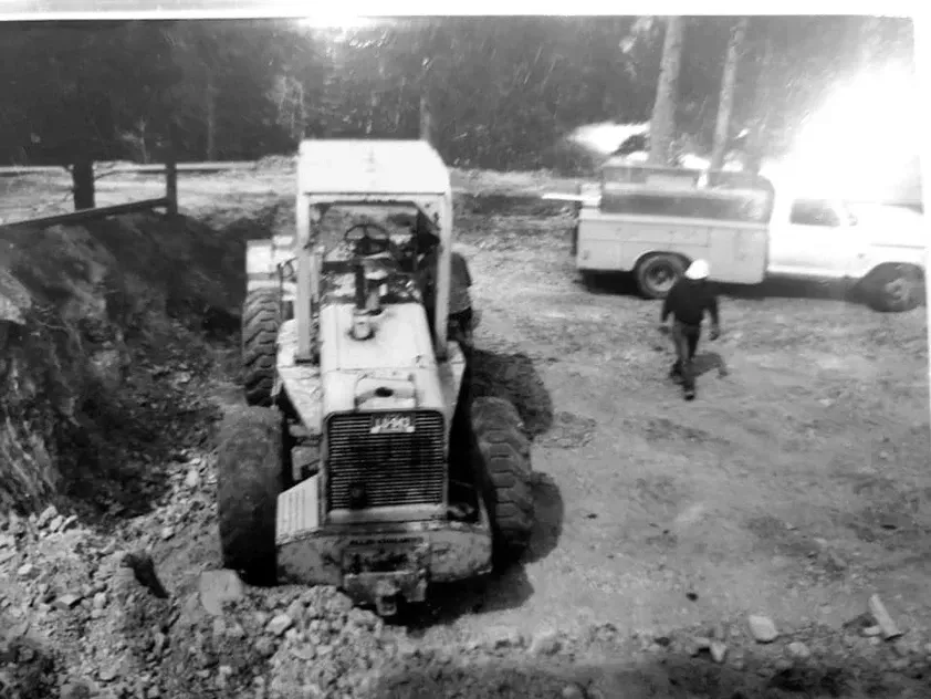 A black and white photo of a tractor and a truck