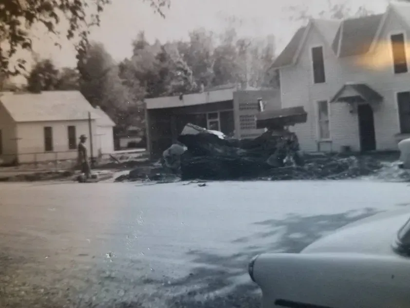 A black and white photo of a house with a car parked in front of it.