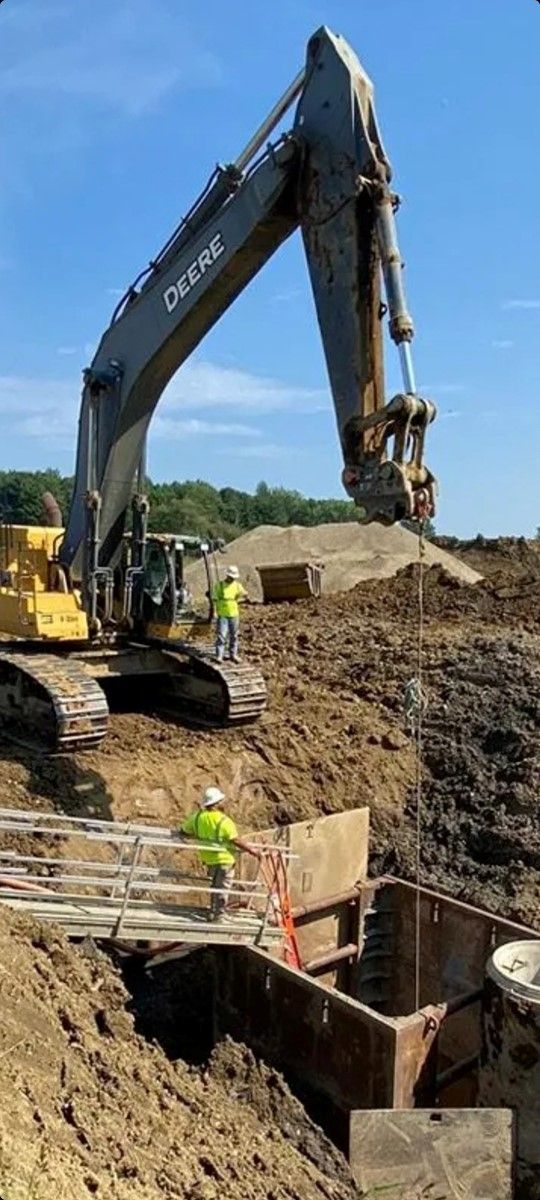 A large excavator is digging a hole in the dirt on a construction site.