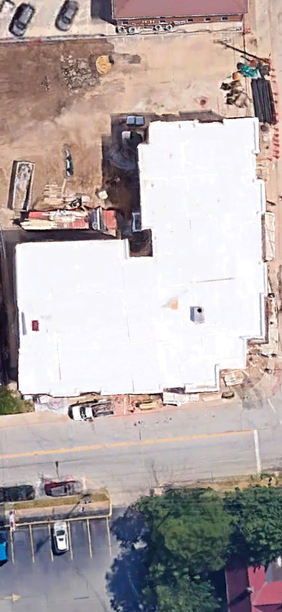 An aerial view of a building under construction with a white roof.